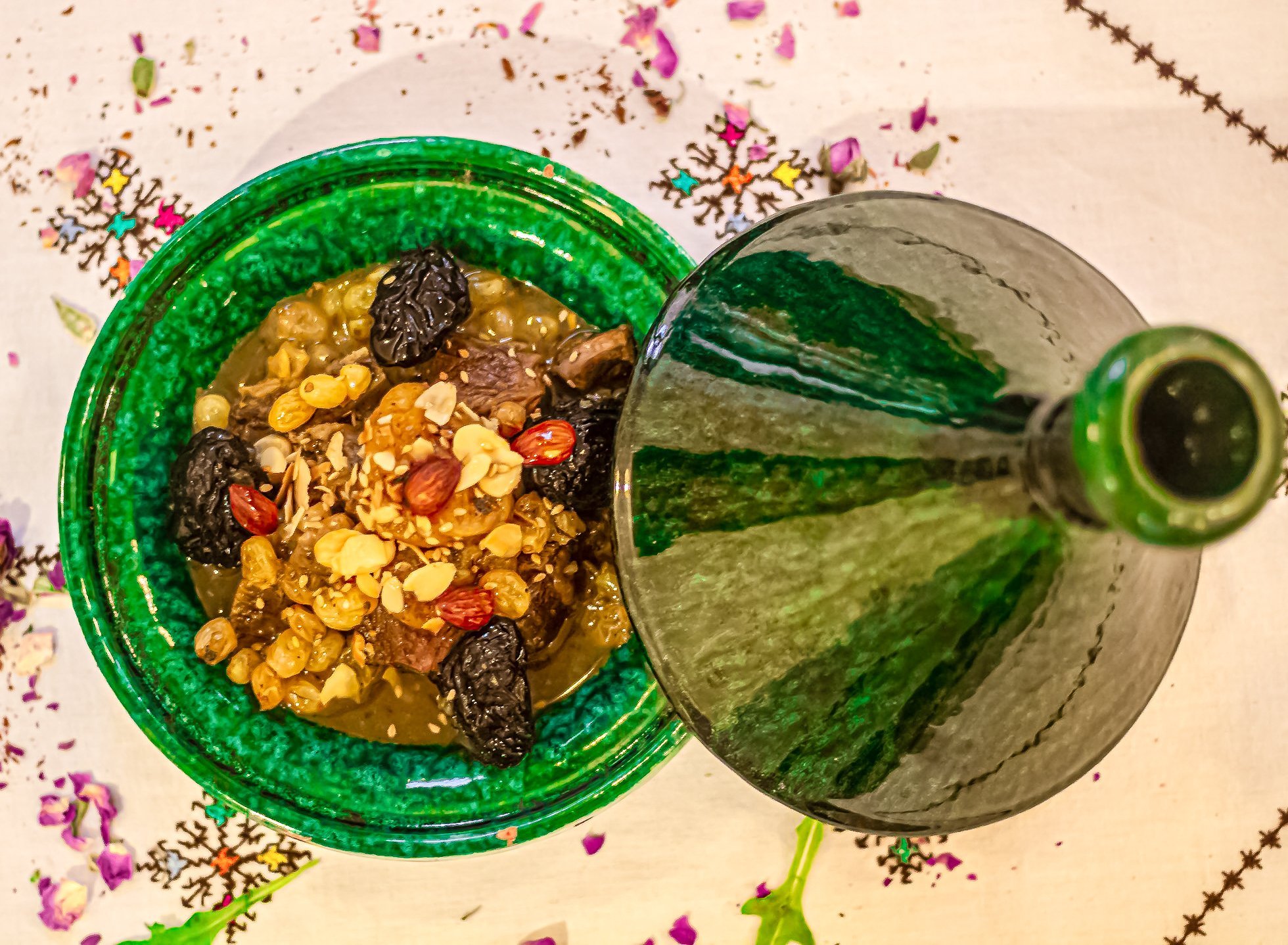 Tajine di carne con prugne e mandorle in un piatto di ceramica verde