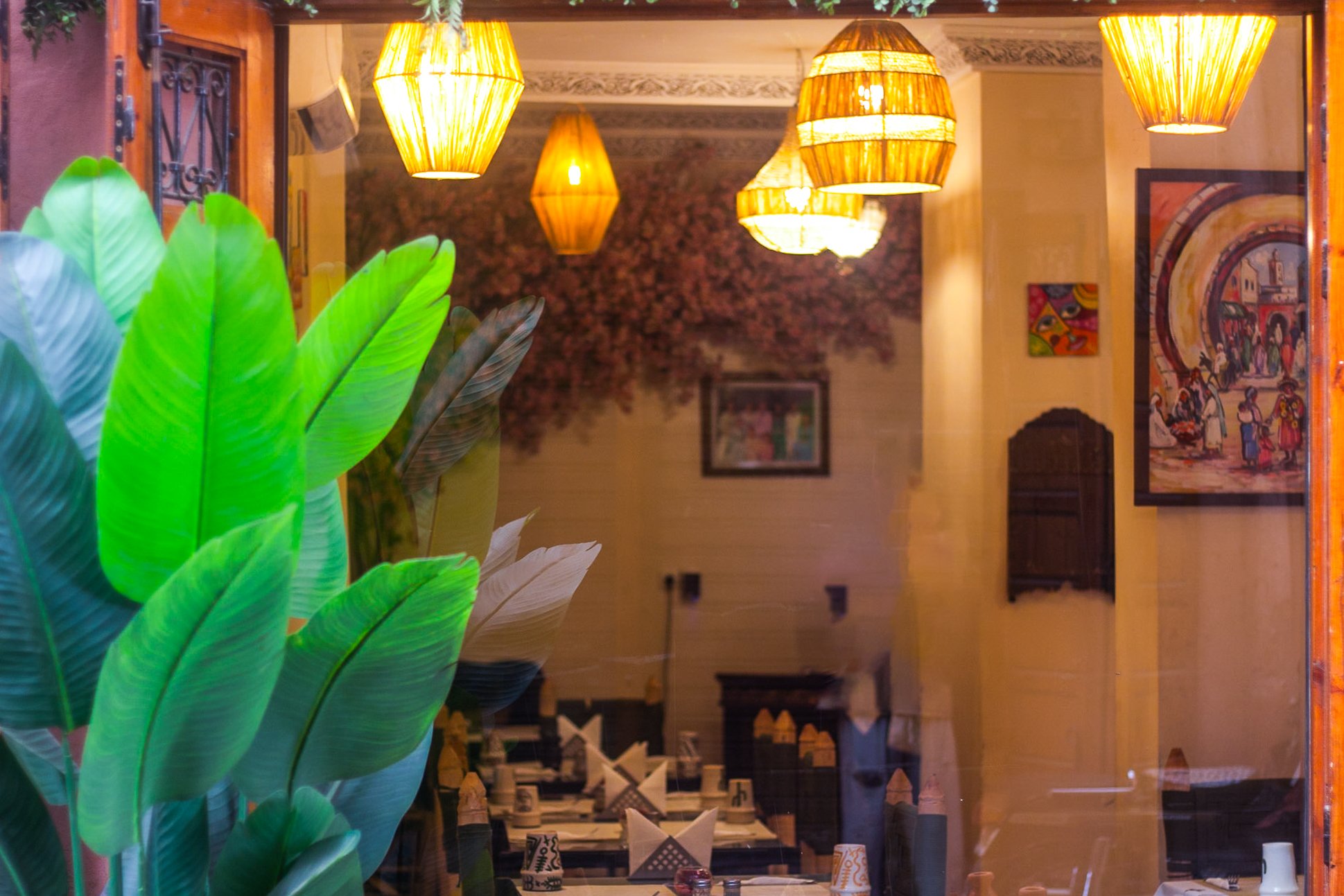 Interior dining room glowing through glass, lanterns lit